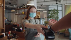 Customer paying with NFC technology by smart watch contactless on terminal in modern cafe, barman woman in medical mask, business reopen after covid coronavirus lockdown - Powered by Shutterstock - Get 15% off with code: PIKWIZARD15