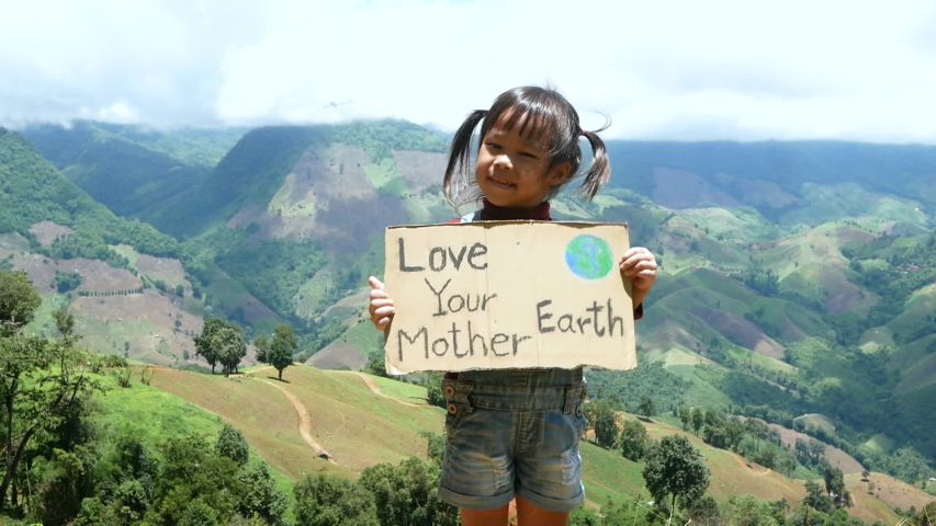 Child girl holding a nature conservation banner in the forest on mountain. The concept of World Environment Day. | Shutterstock HD Video #1056342113