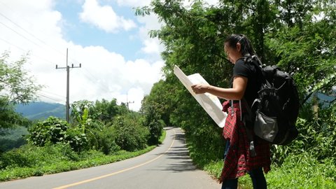 Travel woman backpacking with map by the road during summer vacation trip in amazing landscape nature in Thailand. Traveling and hitchhiking concepts.