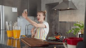 Beautiful woman in kitchen prepares food, takes selfie to their social accounts or video stories with face masks, blogger girl sings in whisk and live broadcast. 