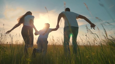 Happy family run in park at sunset. Freedom concept.Teamwork kid. Parents and daughter are run at sunset.Silhouette of run family in park.Success concept. Silhouette of happy family in park. Kid dream