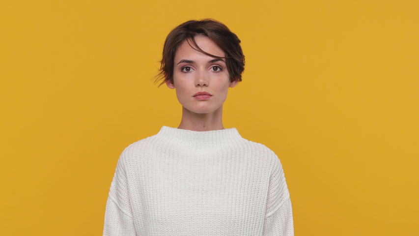 Smiling cute beautiful brunette young woman girl 20s years old in white sweater posing isolated on yellow background in studio. People sincere emotions lifestyle concept. Looking camera charming smile Royalty-Free Stock Footage #1056346310