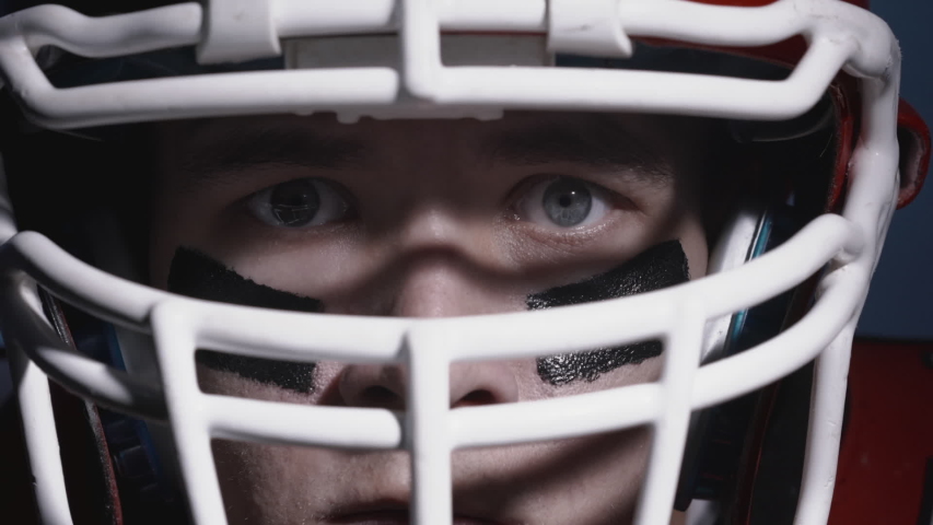 Portrait of self-confident determined American football player in helmet. Closeup of eyes. Confident and agressive man in uniform. Masculine footballer. Usa team game and extreme sport, competition.