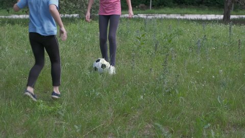 Children play football. Two little sisters play with soccer ball in the park.