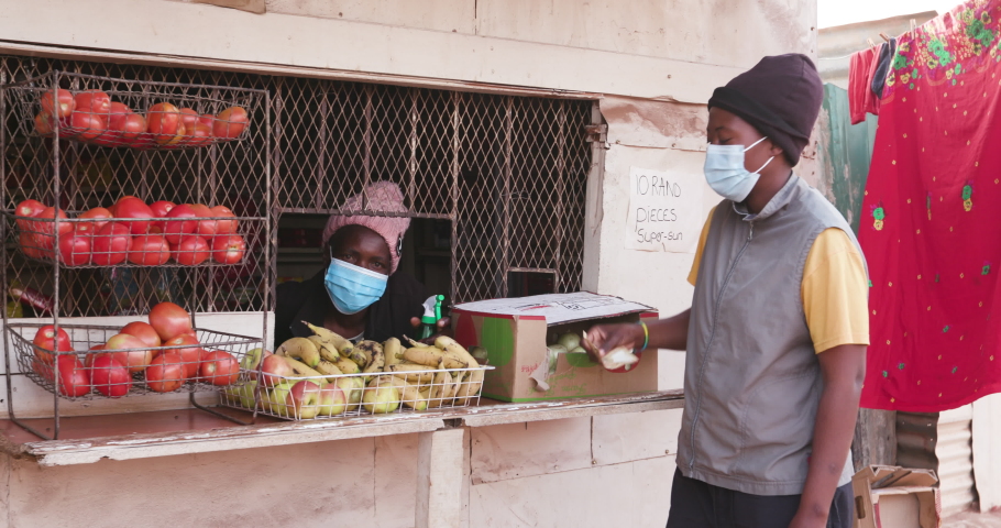 Black African woman buying food from a shop in an informal settlement during Covid-19