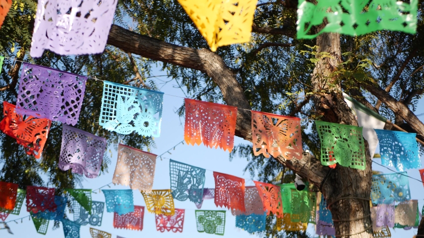 Colorful mexican perforated papel picado banner, festival colourful paper garland. Multi colored hispanic folk carved tissue flags, holiday or carnival. Authentic fiesta decoration in Latin America. Royalty-Free Stock Footage #1056349901