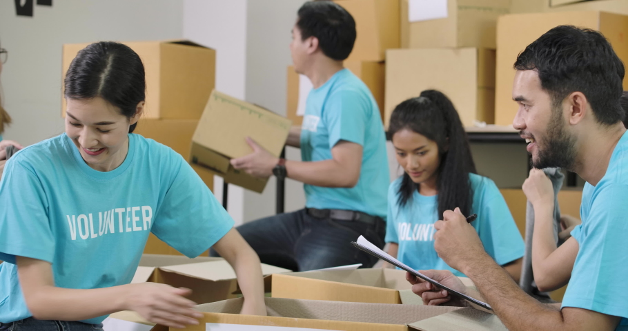 Young asian male and female volunteers sorting clothes in a donation box together as charity workers and members of the community work to the poor during the Coronavirus pandemic. Royalty-Free Stock Footage #1056350348