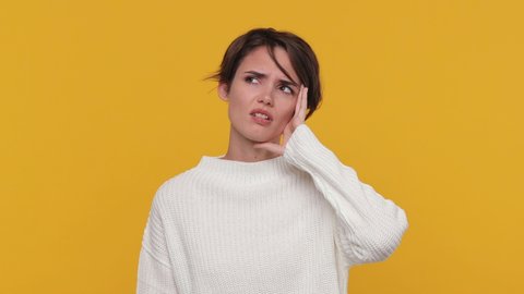Young girl 20s in white sweater did not get enough sleep last night after party barely got up in morning yawning cover mouth with hand isolated on yellow background in studio. People lifestyle concept