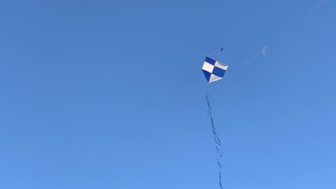 Kite flying on a regular wind and also falling due to the its lack under a blue sky as background