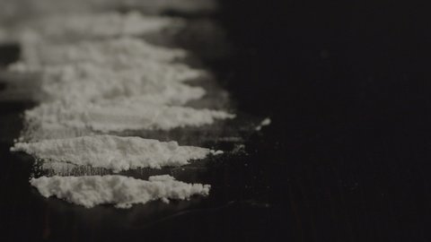 Extreme close of several lines of cocaine powder on black surface