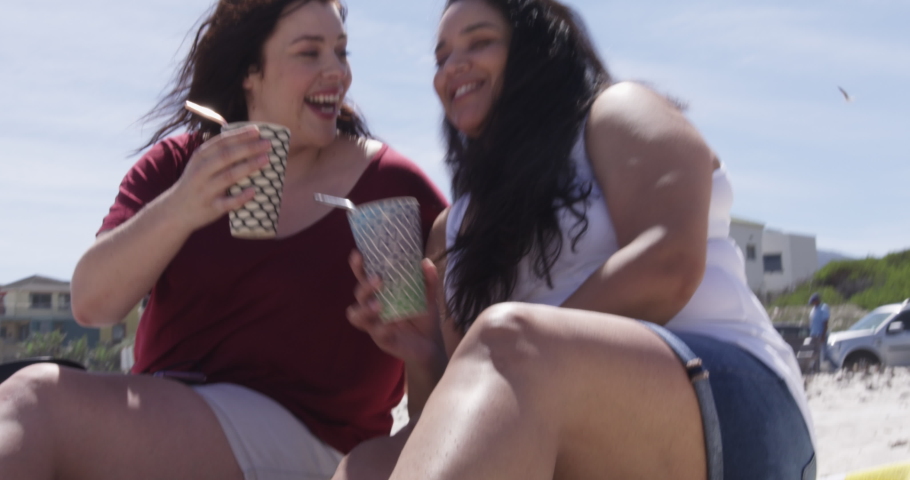 MS Two brunette women sitting on beach and having drinks / Cape Town, South Africa