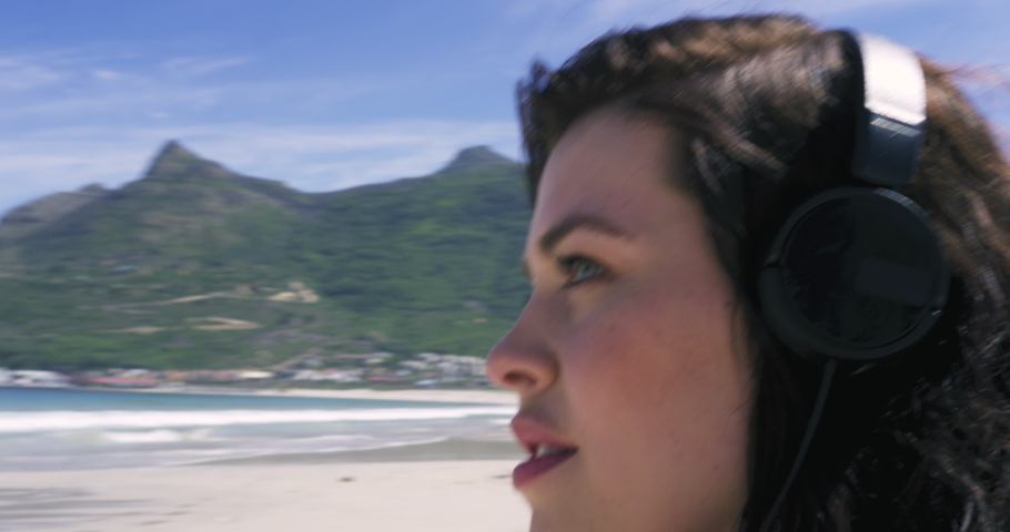 MS TD Brunette woman sitting on beach and listening to music / Cape Town, South Africa