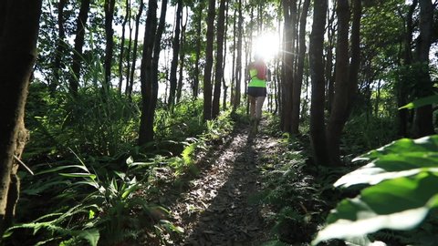 Young woman trail runner running in sunrise tropical forest