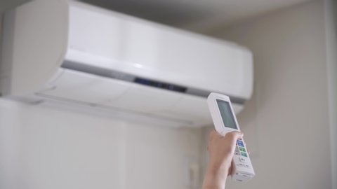 Woman turning on the air conditioner