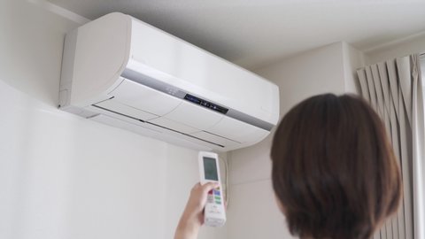 Woman turning on the air conditioner