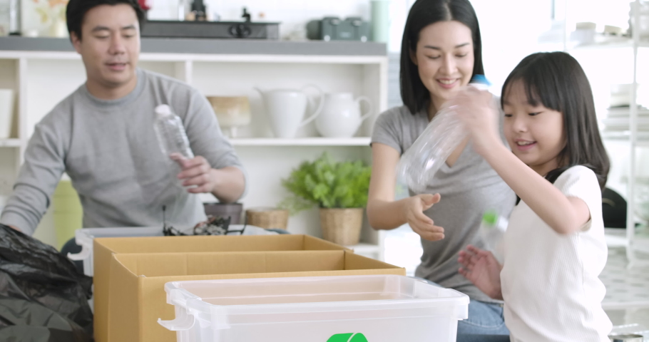Happy responsible young asian family teaching their child sorting home garbage separate trash for further recycling at home together. zero waste, ecological friendly and saving the environment concept | Shutterstock HD Video #1056375119
