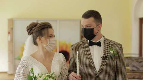 Newlyweds. Lovely young caucasian bride and groom with candle on ceremony. Happy wedding couple family in masks during coronavirus covid-19 pandemic. Slow motion