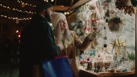 Young couple buys gifts in Christmas fair. Happy couple shopping together. Merry Christmas and Happy New Year! - Powered by Shutterstock - Get 15% off with code: PIKWIZARD15