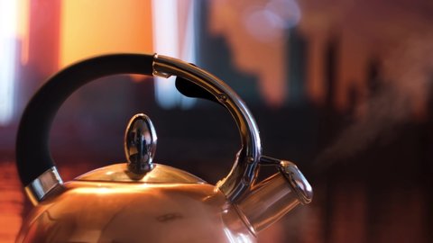A metal silver teapot on a gas stove in the kitchen at home. Concept. Close up of steel kettle with boiling water, preparation of hot beverage.