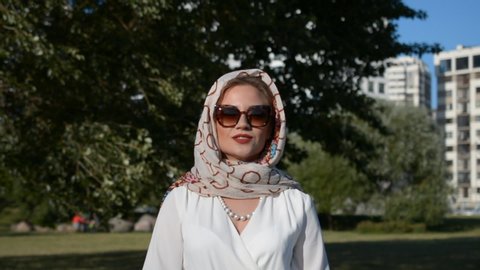 Portrait of a Russian beautiful and elegant woman in a white dress and scarf and in sunglasses hd stock footage outdoor
