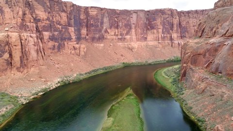 4K aerial slow motion flight in the deep beautiful red canyon with sheer red sandstone cliff walls. Camera moving forward above dramatic surface at beginning of Grand Canyon with green Colorado river