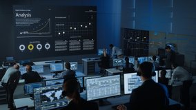 Motion Shot of Professional Traders Working in a Modern Monitoring Office with Live Analytics Feed on a Big Digital Screen. Monitoring Room Brokers and Finance Specialists Sit in Front of Computers. - Powered by Shutterstock - Get 15% off with code: PIKWIZARD15