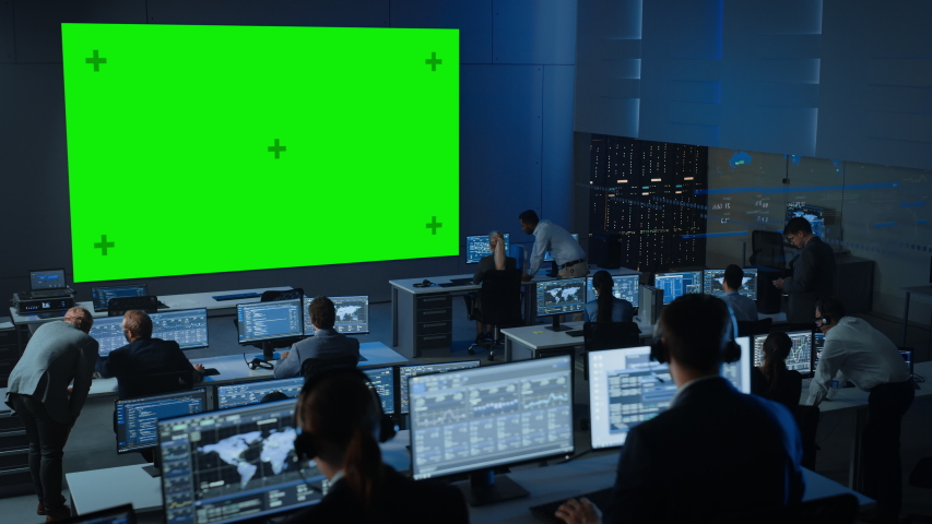 Big Green Screen Horizontal Mock Up in a Control Center Room with Engineers and Controllers Working on Computers. Team of Telecommunication Employees Work in Monitoring Room Full of Displays. | Shutterstock HD Video #1056388088