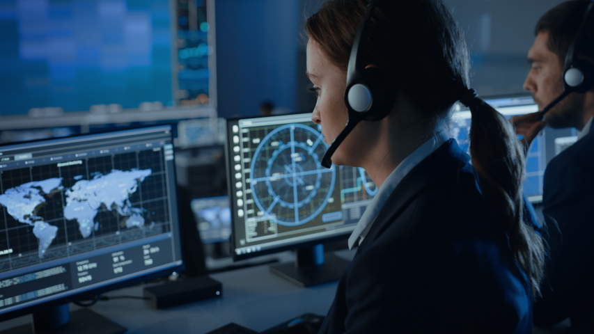 Computer Screen with Global Map Technology Used by a Female Flight Controller in a Mission Control Center Room with Other Scientists. Team of Engineers Work in Monitoring Room Full of Displays. | Shutterstock HD Video #1056388121