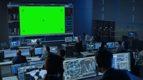 Big Green Screen Horizontal Mock Up in a Mission Control Center Room with Flight Director and Other Controllers Working on Computers. Team of Engineers Work in Monitoring Room Full of Displays.