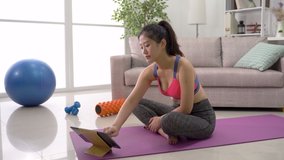 slender Asian watching online training program to practice yoga lotus pose. indoor recreation female learn how to meditate with the help of internet.