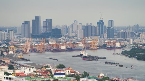 Time lapse of aerial view of container cargo ship in the export and import business and logistics international goods in urban city. Shipping to the harbour by crane in Bangkok harbour, Thailand.