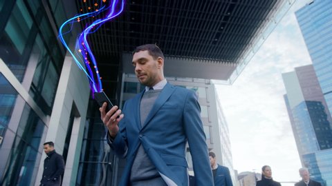 Handsome Businessman Uses Smartphone with Animated Abstract Digital Data Lines Flying, Walks on Crowded City Streets. Big Data, Information, e-Business Concept. Low Angle Front View Following Shot
