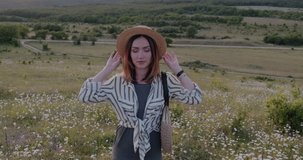 Beautiful happy young girl enjoying nature among the mountains, blooming daisies. Slow motion video