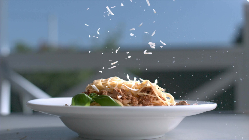 Pasta with Cheese Plate Sitting on a Table and Parmesan is Falling on Basil and Spaghetti in Slow Motion 4K Royalty-Free Stock Footage #1056392201
