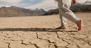 Close up shot of legs of baby boy running on cracked ground, destroyed by erosion, desertification and global warming - environmental issues, save our planet 4k footage