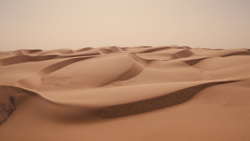 Aerial drone shot sweeping over perfect Sahara desert sand dunes as far as the eye can see that disappear into the distance Royalty-Free Stock Footage #1056393566