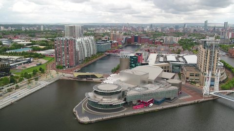 Manchester, England - August 15th 2018: Aerial drone shot of Salford Quays with the city of Manchester in the background, flying down the river on a cloudy day
