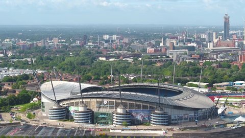 Manchester, England - August 15th 2018: Aerial drone long lens shot of the Manchester City Etihad Football stadium with the city of Manchester in the background on a sunny cloudy day