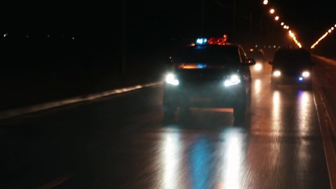 Police cars are chasing an intruder's car in the hard rain. Outdoor front view of police traffic auto driving. 