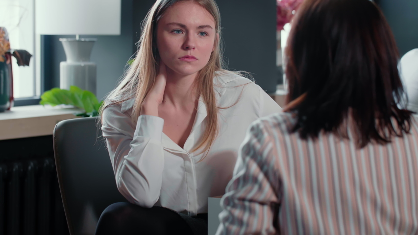 Positive young beautiful gen-z Caucasian blonde female CEO listening to employee woman at modern office meeting table. Royalty-Free Stock Footage #1056408230