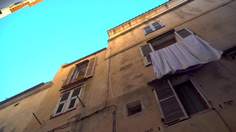 The laundry dries under the window. Panoramas of narrow streets in a small European, French or Italian old town by the sea in the mountains. Lifestyle. Blue sky.