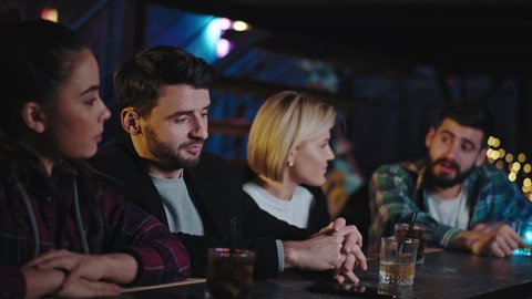 Attractive young people friends sitting on a bar and spending a great time together they chatting drinking some cocktails smiling and feeling great. Shot on ARRI Alexa Mini