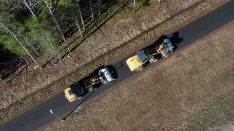 Top-down aerial of two street sweeping tractors next to a forest. Spring cleaning on roads