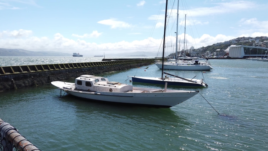 A white boat docked in Oriental Bay Wharf in Wellington New Zealand on a sunny day.