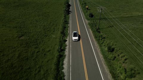 A White Car Driving On The Asphalt Road In Quebec, Canada On A Bright Weather - ascending drone shot (backward)