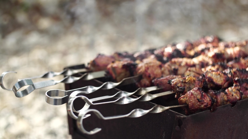 Close-up of grilling tasty dish on barbecue. Process of cooking yummy shashlik in nature. Delicious food on metal skewer in bbq. Time to picnic concept. Street food. Food festival. Pork at the stake Royalty-Free Stock Footage #1056421850