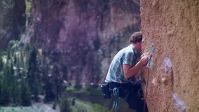 Young climber clips in bolt as he ascends arete in Smith Rock national nark