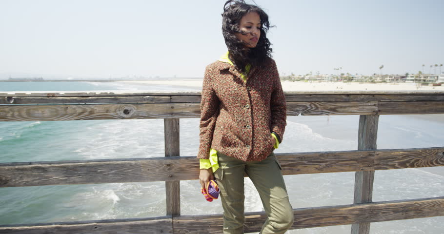 Beautiful young black woman absorbing the cool sea breeze from the pier