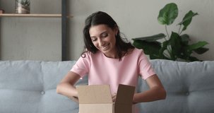 Pretty Indian woman customer sit on sofa unpack package open parcel. Girl consumer receive purchased goods in online shop feels happy, post mail shipping, prepare delivery for send to relative concept