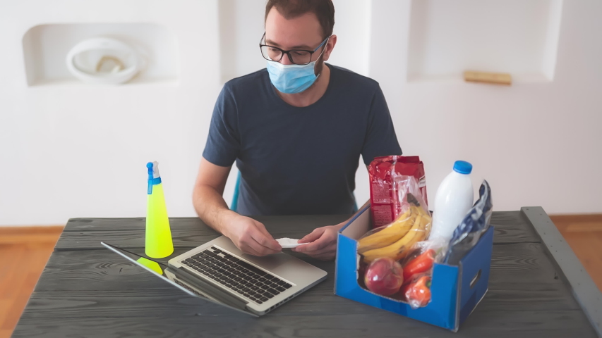 Salesman sterilizing food prepared for order over the internet during the virus outbreak worldwide. Shopping / buying / ordering groceries and food remotely using laptop and internet.	
 | Shutterstock HD Video #1056430790
